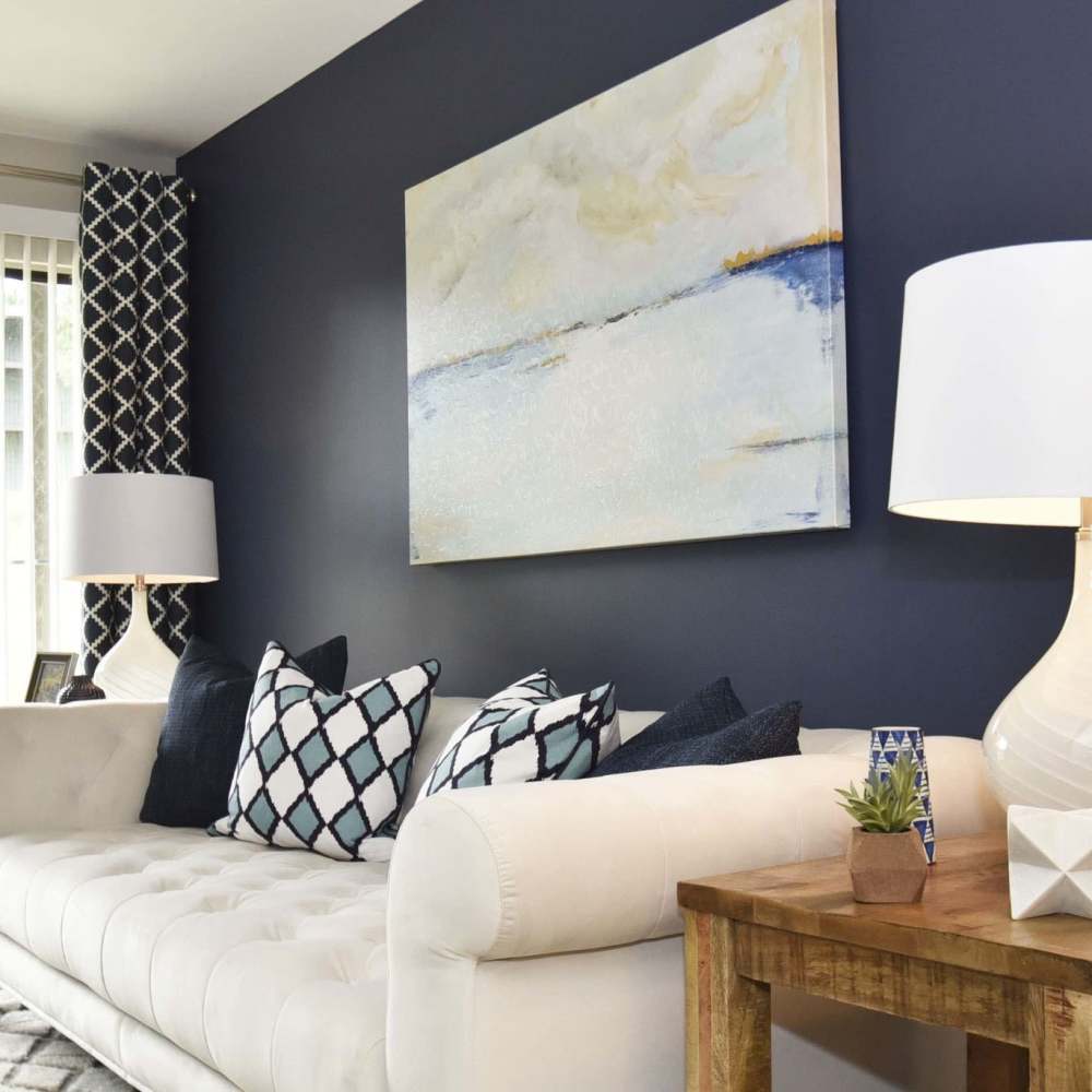 Apartment living area with couch and a wall painting at Sona at Harding in Nashville, Tennessee