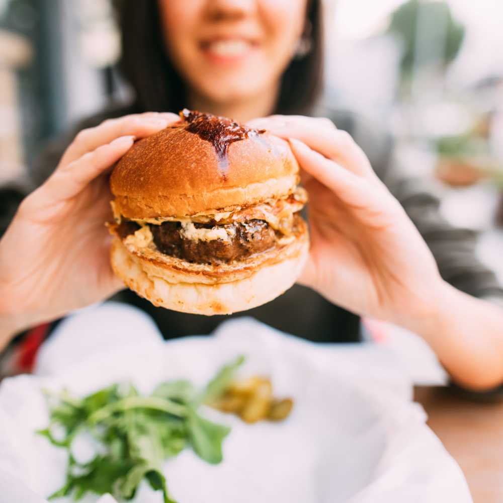 Resident about to dive into a delicious burger at her favorite restaurant near 10 Newbridge in Asheville, North Carolina