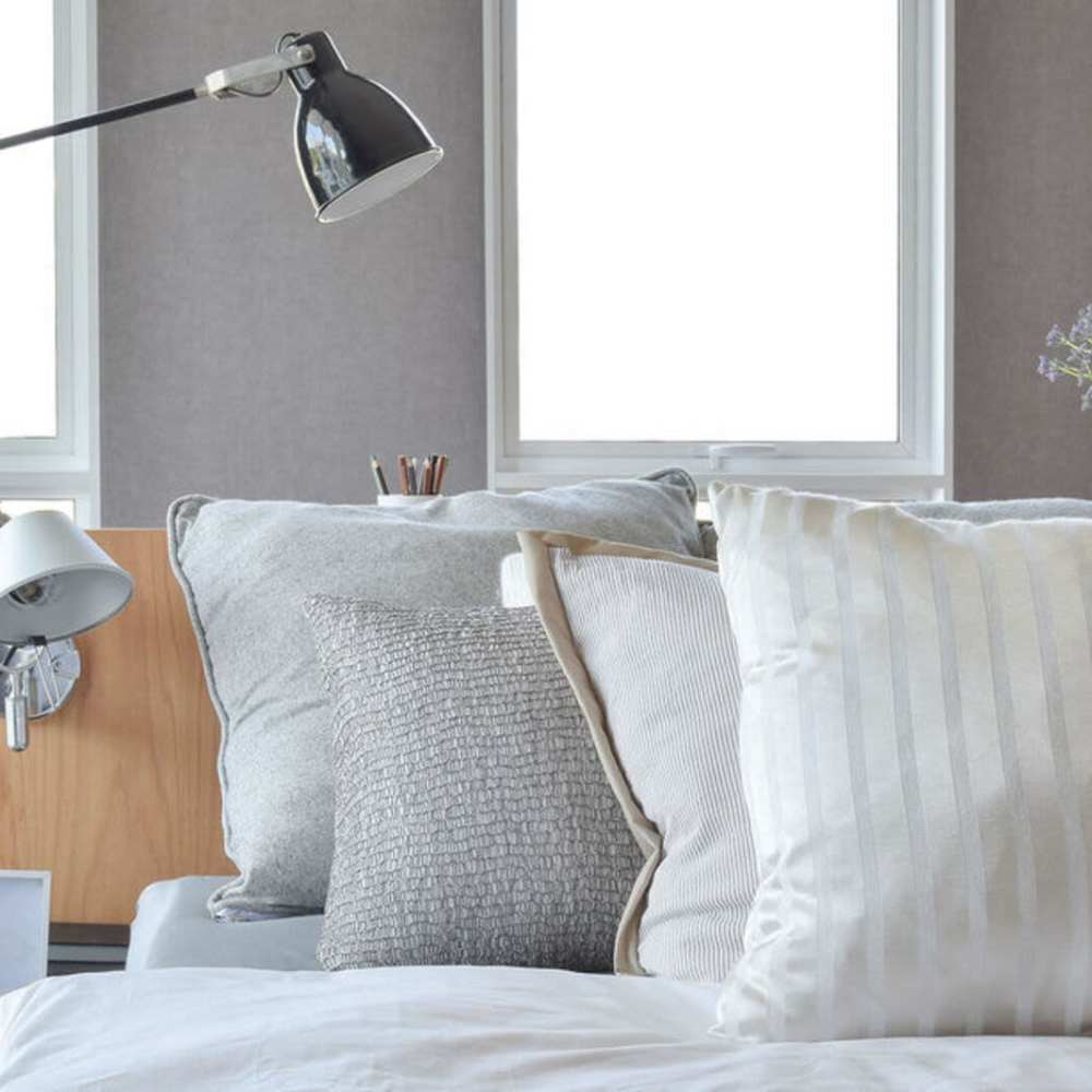 A comfortable bed with decorative pillows and a lamp on the side at Broadway Street Apartments in Lowell, Massachusetts