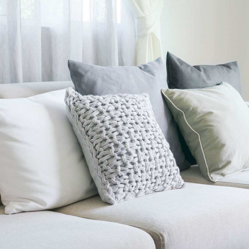 A living room scene showcasing a couch with multiple pillows arranged at Broadway Street Apartments in Lowell, Massachusetts