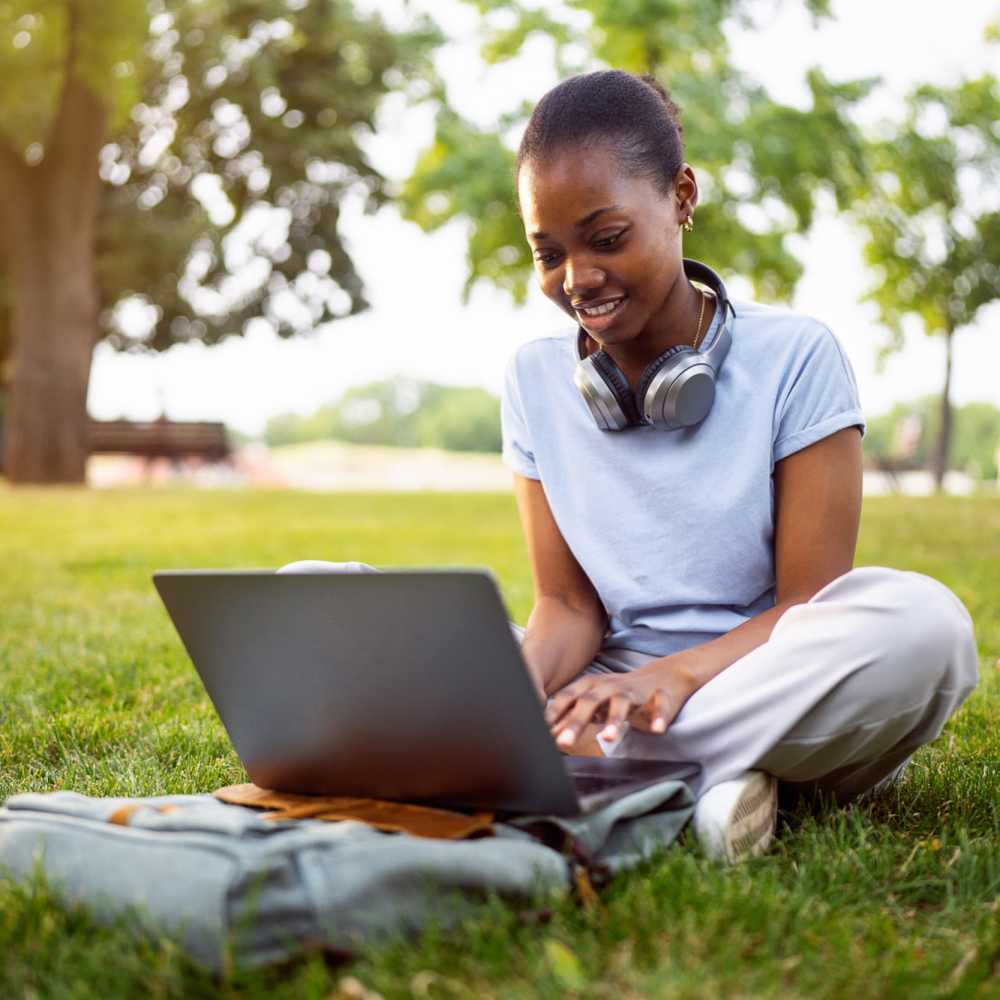 A girl working on her laptop at a park near The Edge in Pensacola, Florida