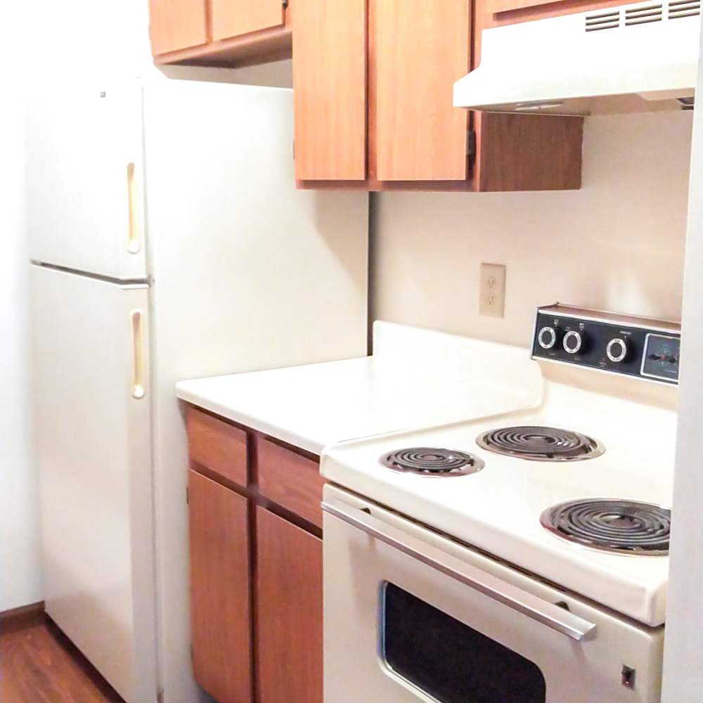 Kitchen with wooden cabinetry, range and oven at Mill Pond (Brooklyn) in Brooklyn, Michigan
