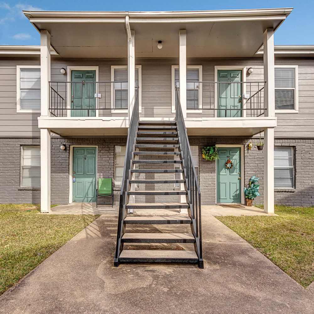 Exterior view of the apartment building with stairs leading to the first floor at The Grand 1501 in College Station, Texas