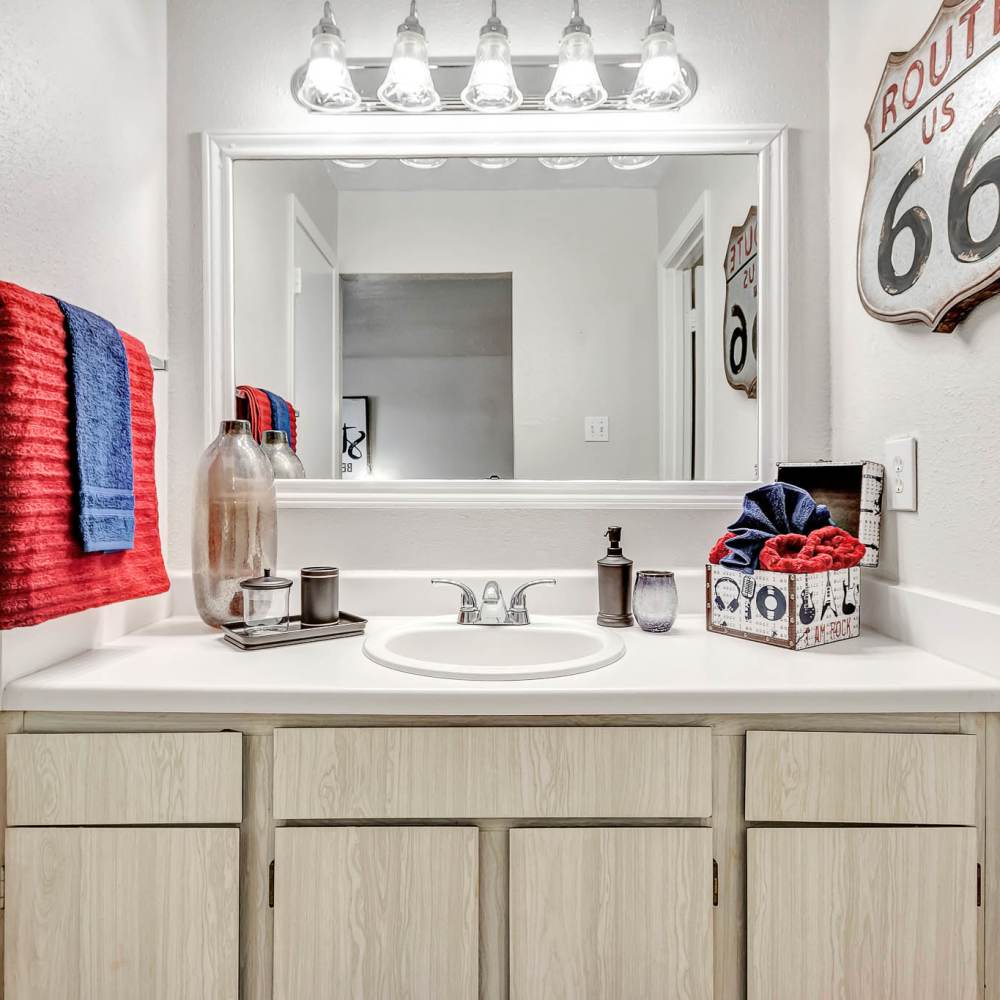 Bathroom with a large mirror and wooden cabinets at The Grand 1501 in College Station, Texas
