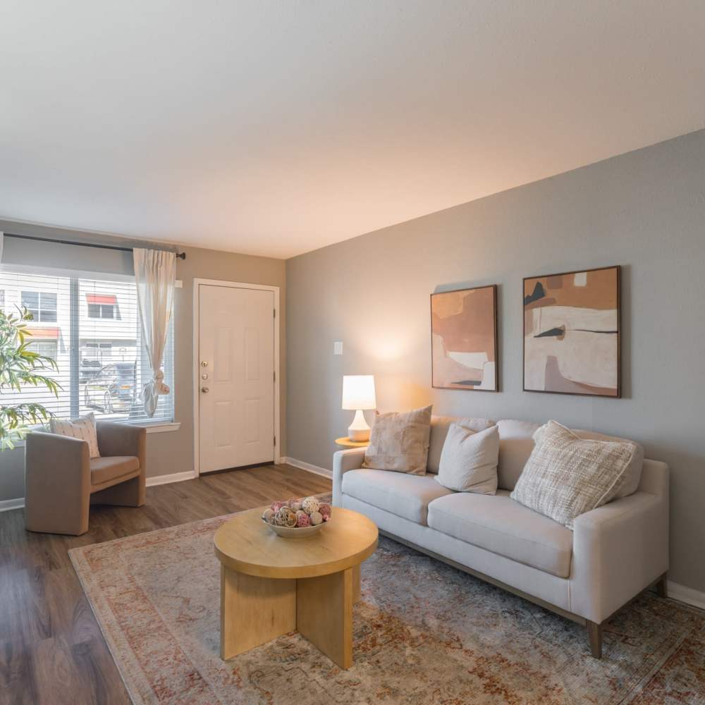 Living room with a comfortable couch, coffee table and a large window at The Grand 1501 in College Station, Texas