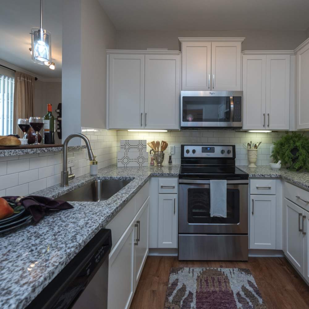 Fully-equipped kitchen with stainless steel appliances and steel sink and pendant lights at Avonlea On The River in Duluth, Georgia
