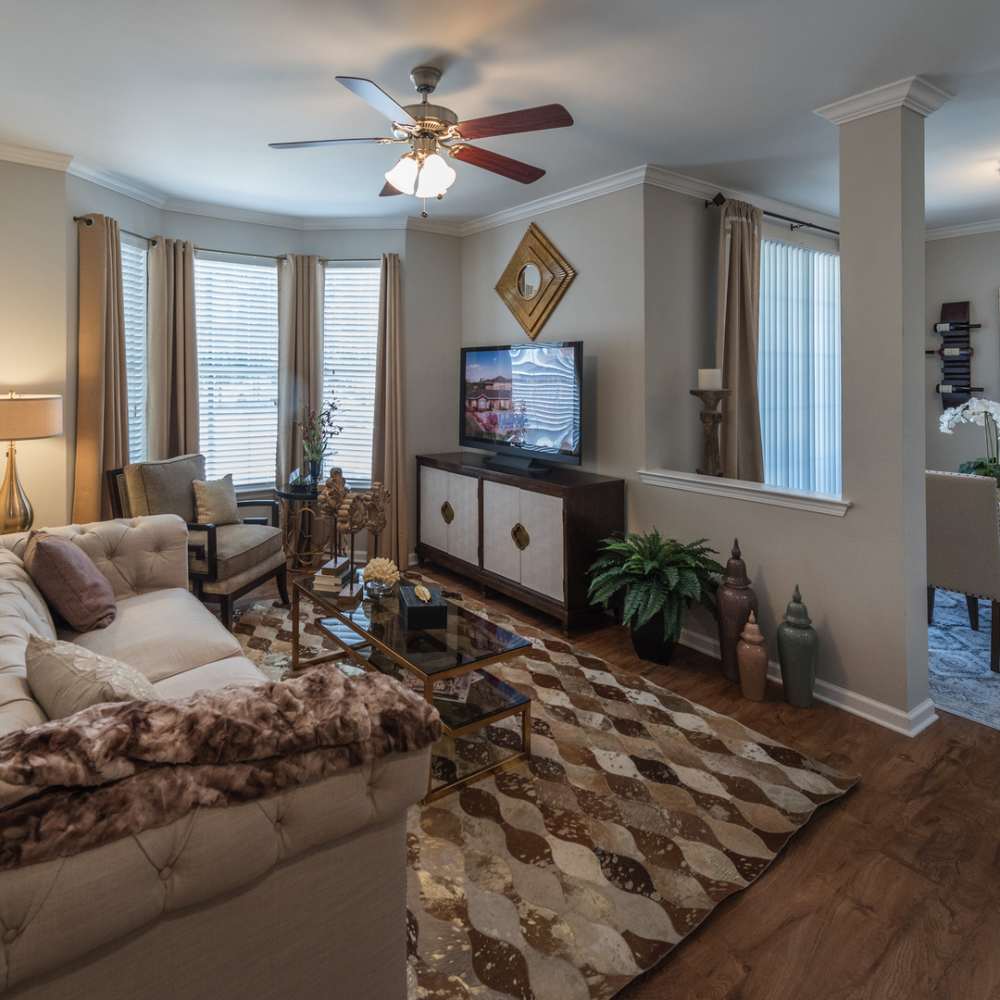 Open layout living room with hard-wood style flooring and plenty of room for a couch, chair, TV, plants at Avonlea On The River in Duluth, Georgia