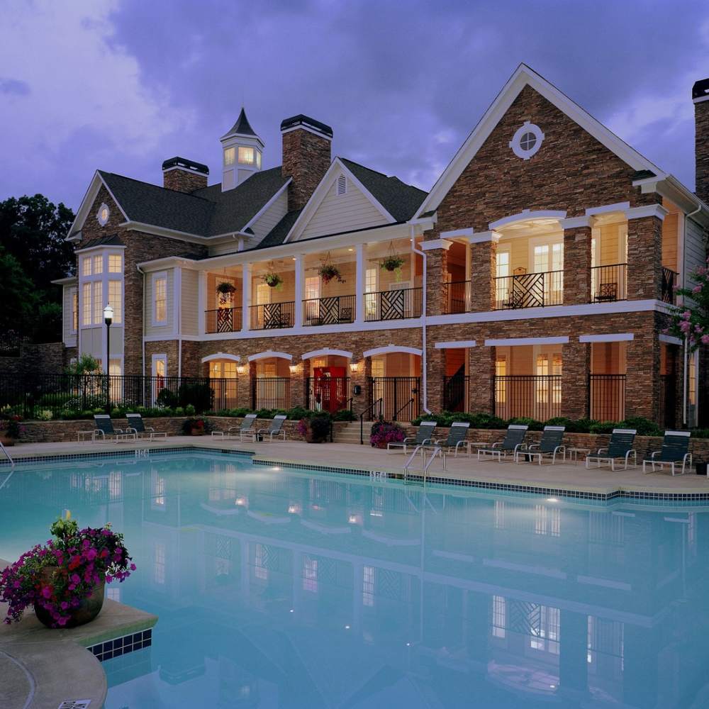 Resort-style large swimming pool with lounge chairs and view of clubhouse at Avonlea On The River in Duluth, Georgia