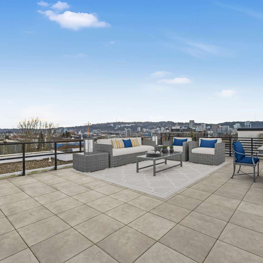 Spacious rooftop terrace with gray tile flooring and wicker furniture at Koz on 13th in Portland, Oregon
