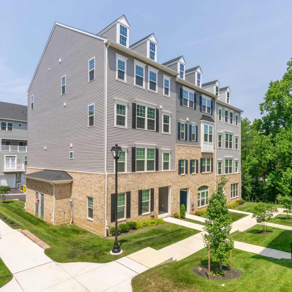 Exterior view of an apartment complex with a lawn and trees at Dorsey Overlook in Ellicott City, Maryland.