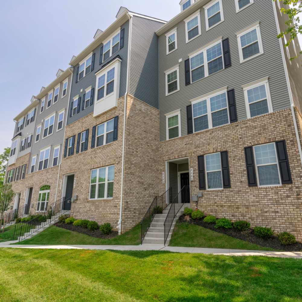 View of an apartment building surrounded by a lawn and trees at Dorsey Overlook in Ellicott City, Maryland.