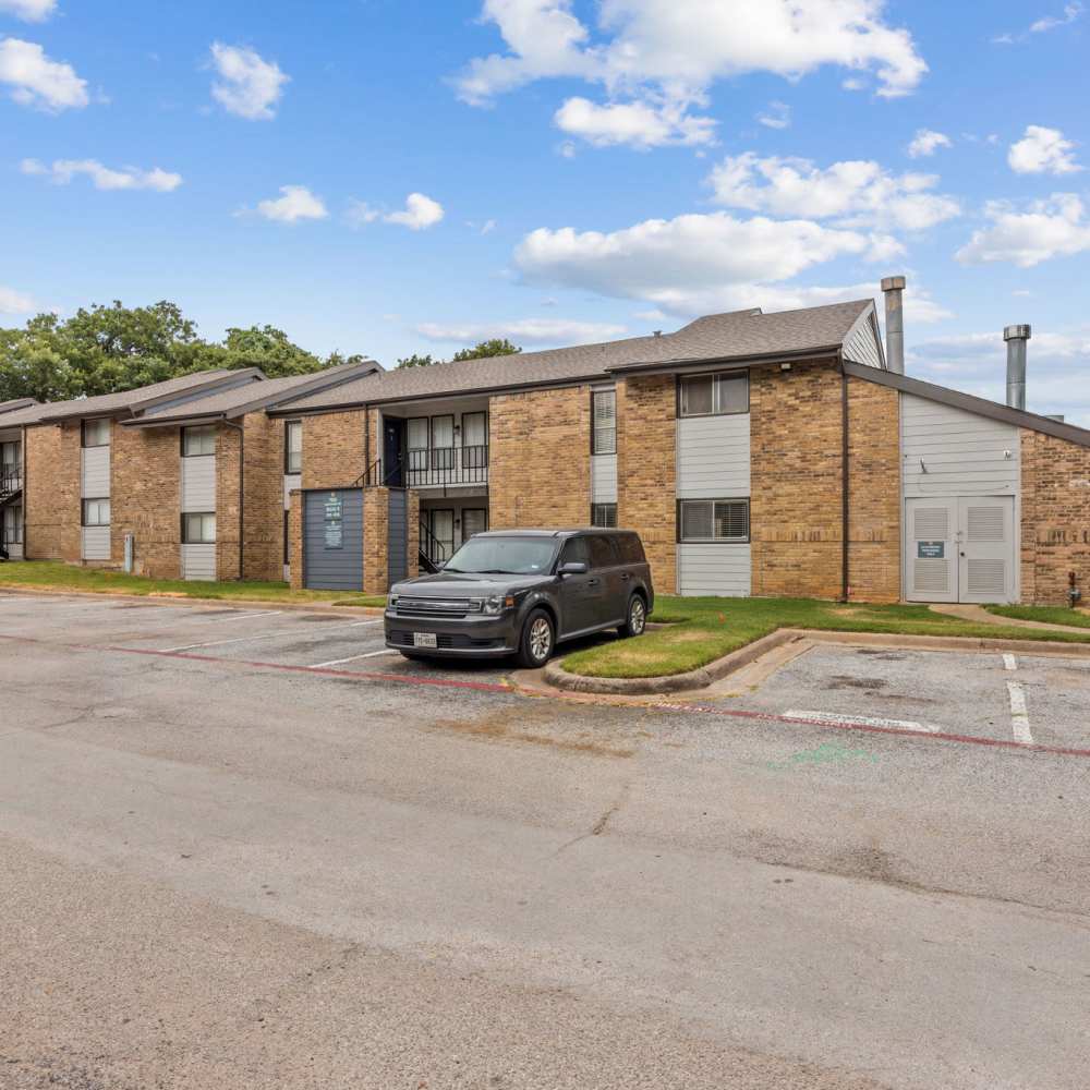 Apartment complex exterior with a car parking at The Madeleine in Fort Worth, Texas
