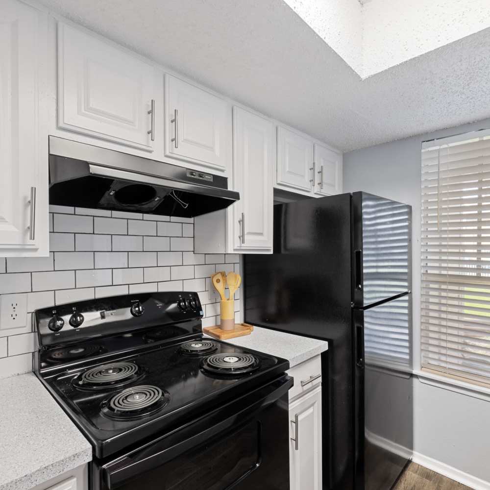 Modern kitchen with kitchen stove, hanging cabinets and refrigerator at The Madeleine in Fort Worth, Texas