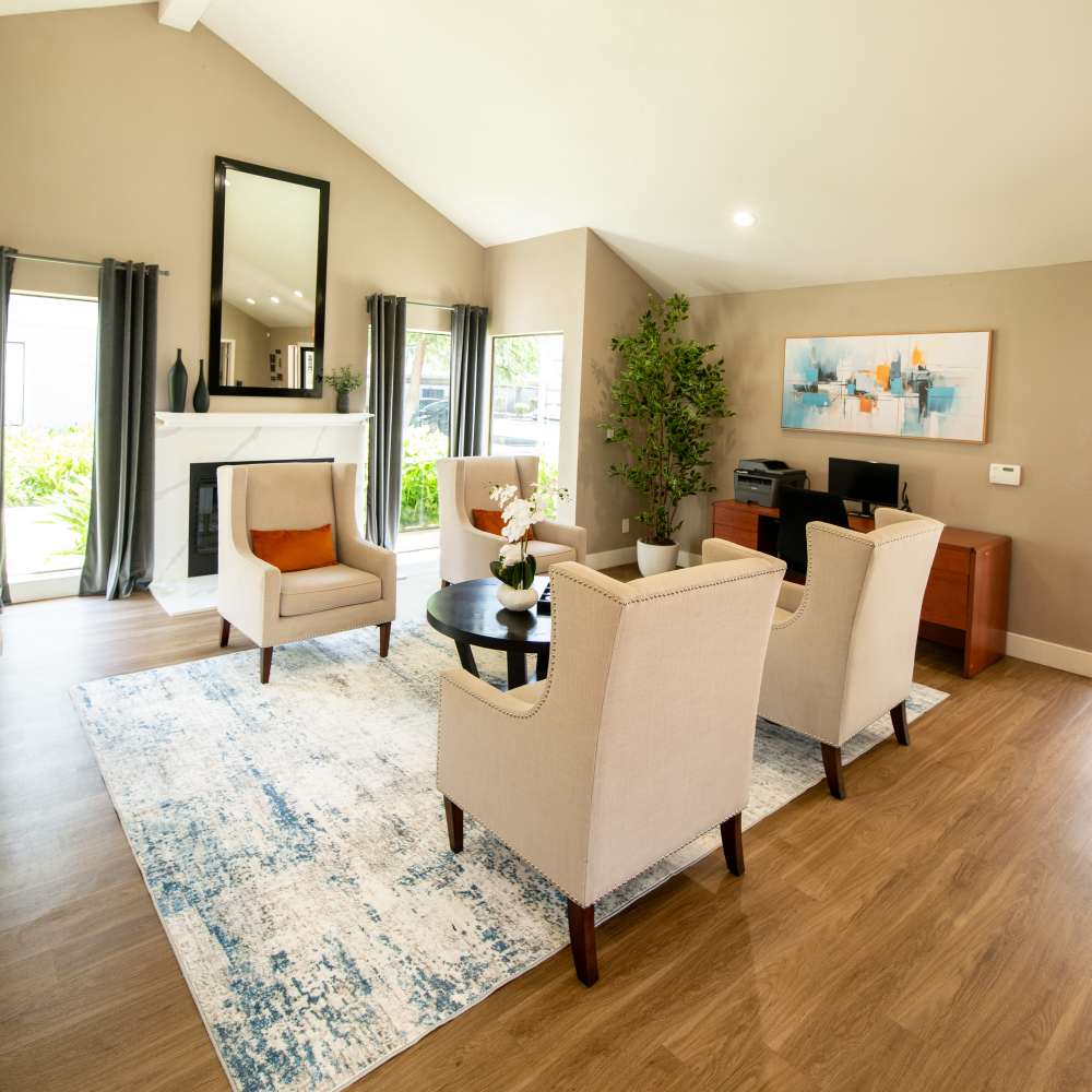 Cozy lounge area with chairs, a coffee table, and a fireplace at Riverstone Apartment Homes, featuring modern decor. at Riverstone Apartments in Sacramento, California