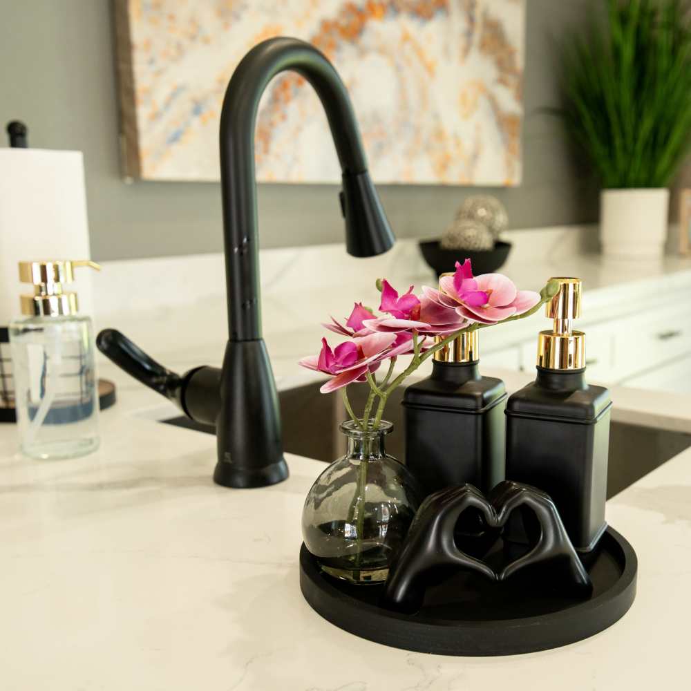 Elegant countertop display with a black faucet, decorative bottles, and a vase of orchids at Riverstone Apartment Homes at Riverstone Apartments in Sacramento, California