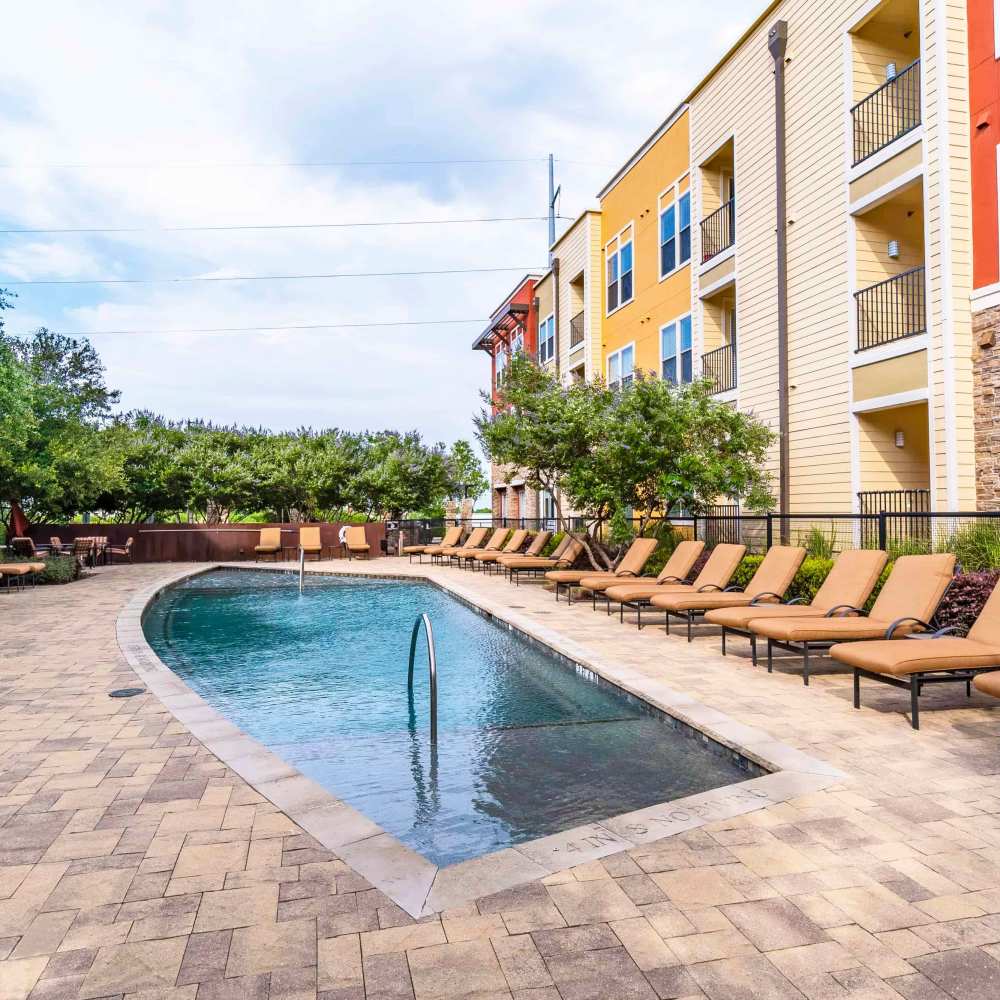 Community pool with a sun loungers by the deck at Grapevine Station in Grapevine,Texas