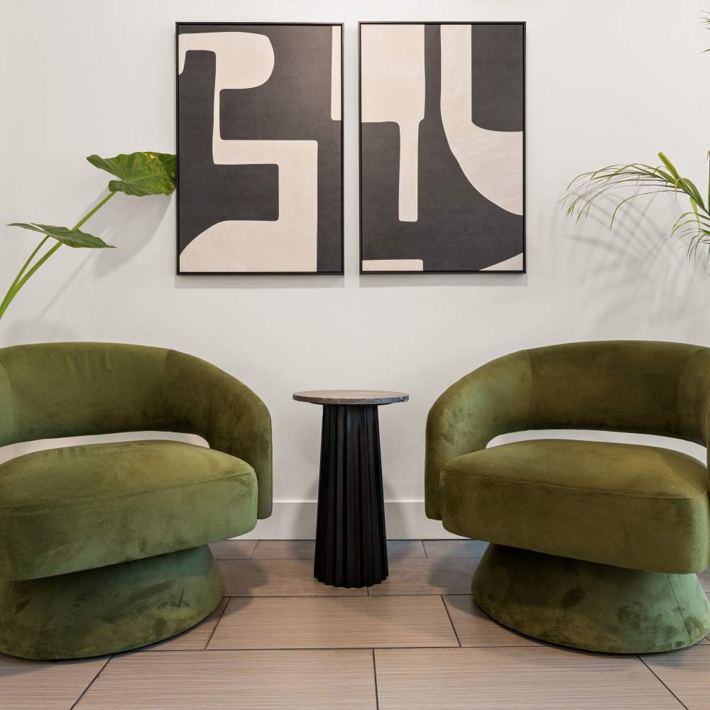 Seating area with two green upholstered chairs and a black pedestal side table at Canyon Village in North Hollywood, California