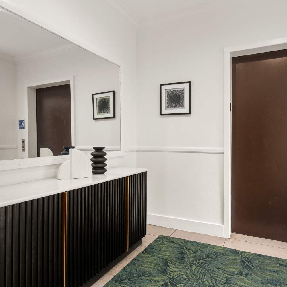 Modern hallway corner with a dark wood console topped with decorative accents at Canyon Village in North Hollywood, California