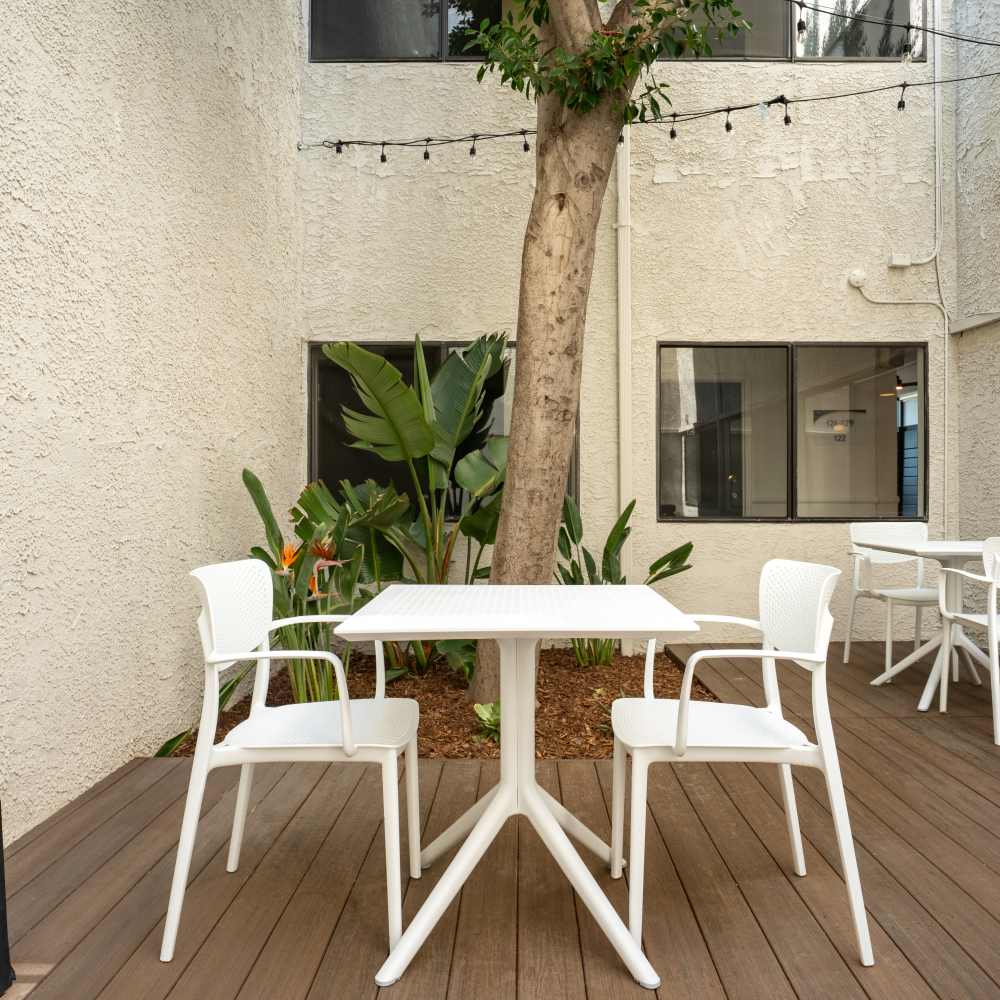Modern courtyard with white tables and chairs at Canyon Village in North Hollywood, California