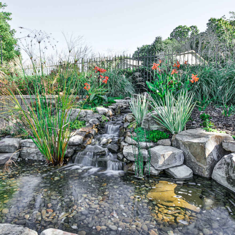 Tranquil water feature surrounded by vibrant flowers and lush greenery at Avonlea Riverside in Atlanta, Georgia