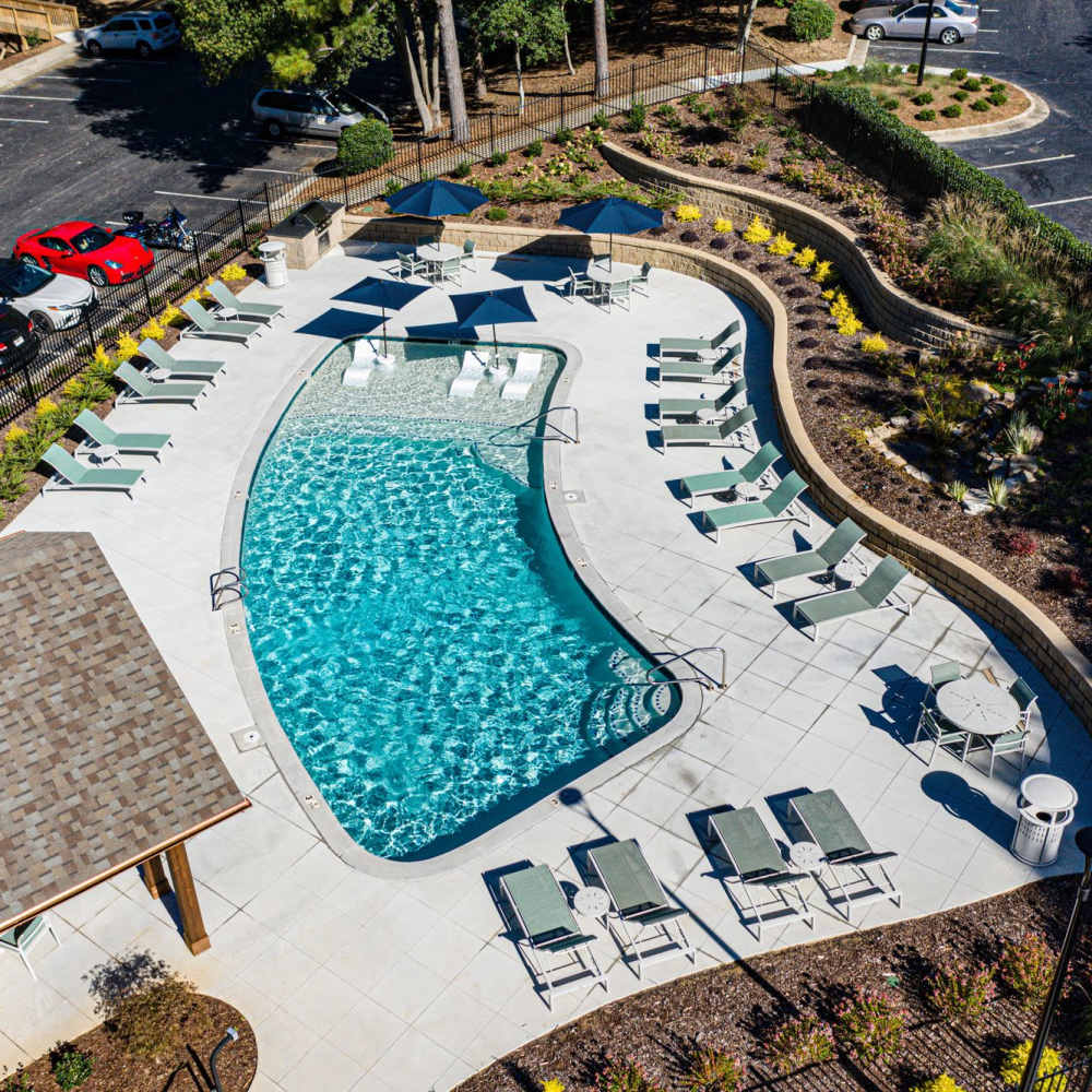 Sparkling pool surrounded by lounge chairs and lush landscaping at Avonlea Riverside in Atlanta, Georgia