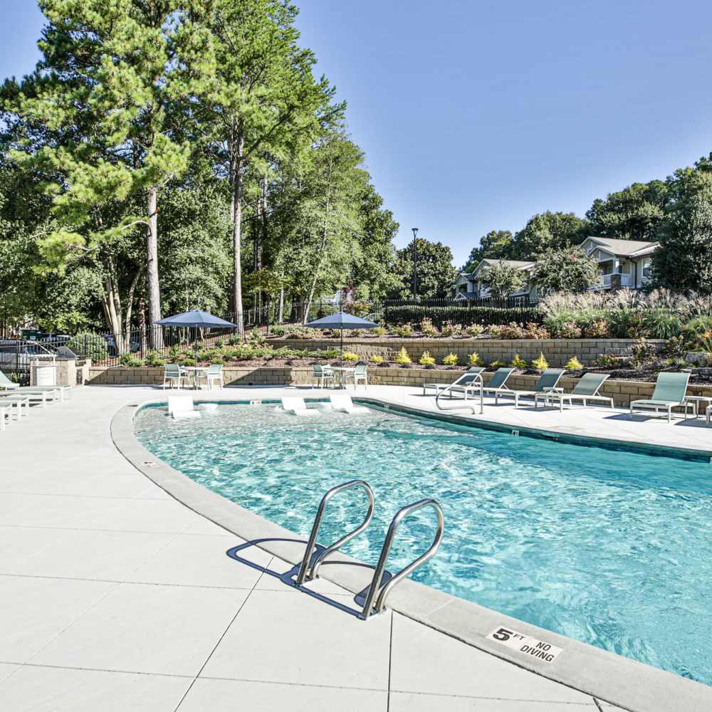 Sparkling pool surrounded by lush greenery and comfortable lounge chairs at Avonlea Riverside in Atlanta, Georgia