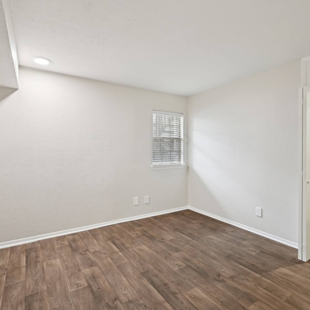 Bright, empty room with modern wood flooring and natural light at Woodlands of Plano in Plano, Texas