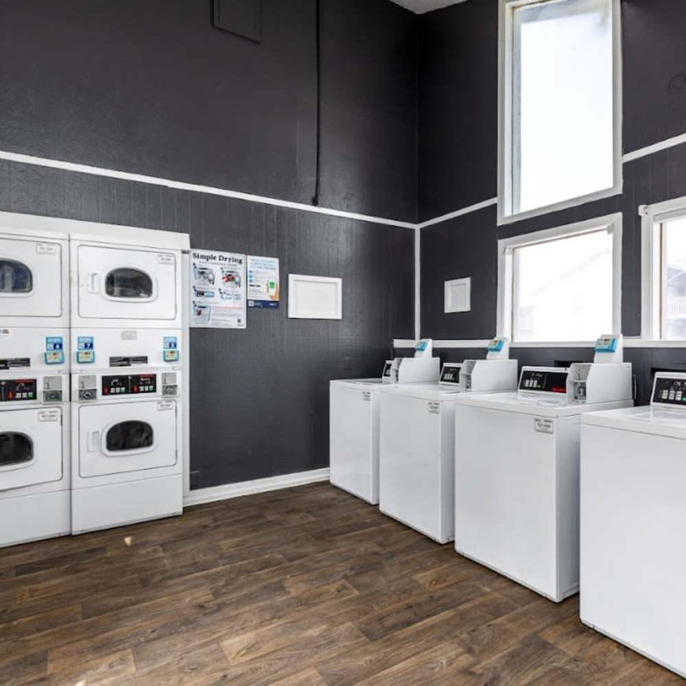 Bright laundry room with modern washers and sleek finishes at Woodlands of Plano in Plano, Texas
