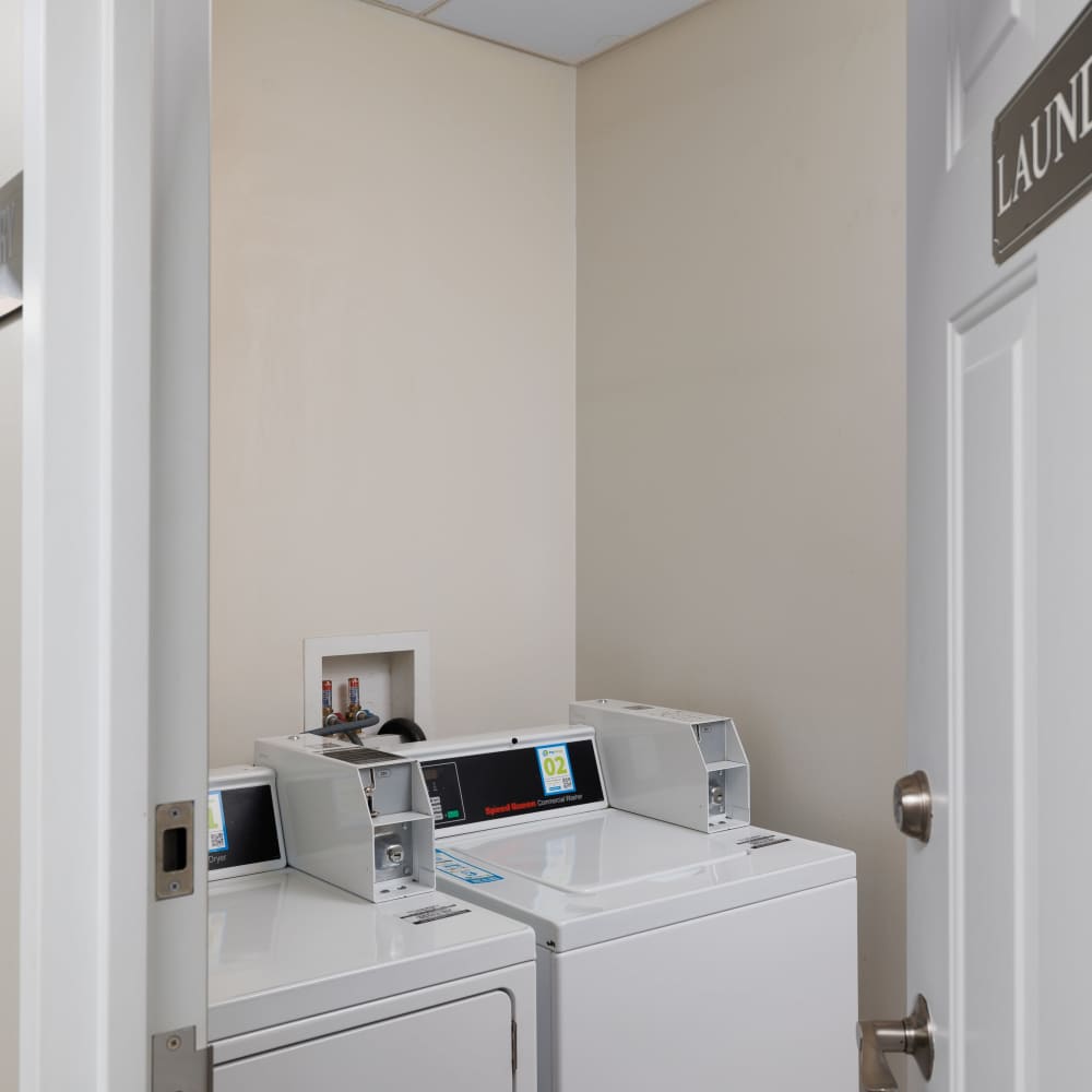 Community laundry room with a washer and dryer at Del Coronado Apartments in St. Louis, Missouri