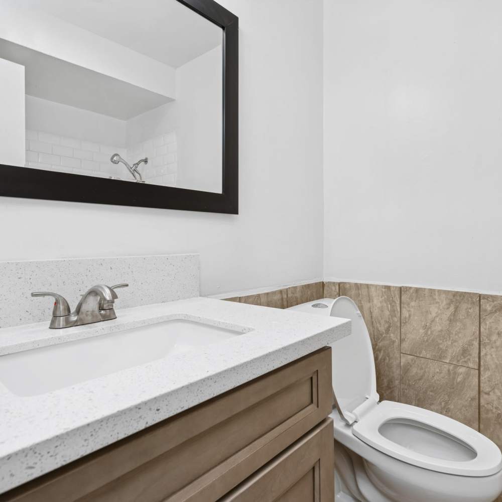 Bathroom with framed mirror, sink, commode and storage space at Newland Garden Apartments in Garden Grove, California