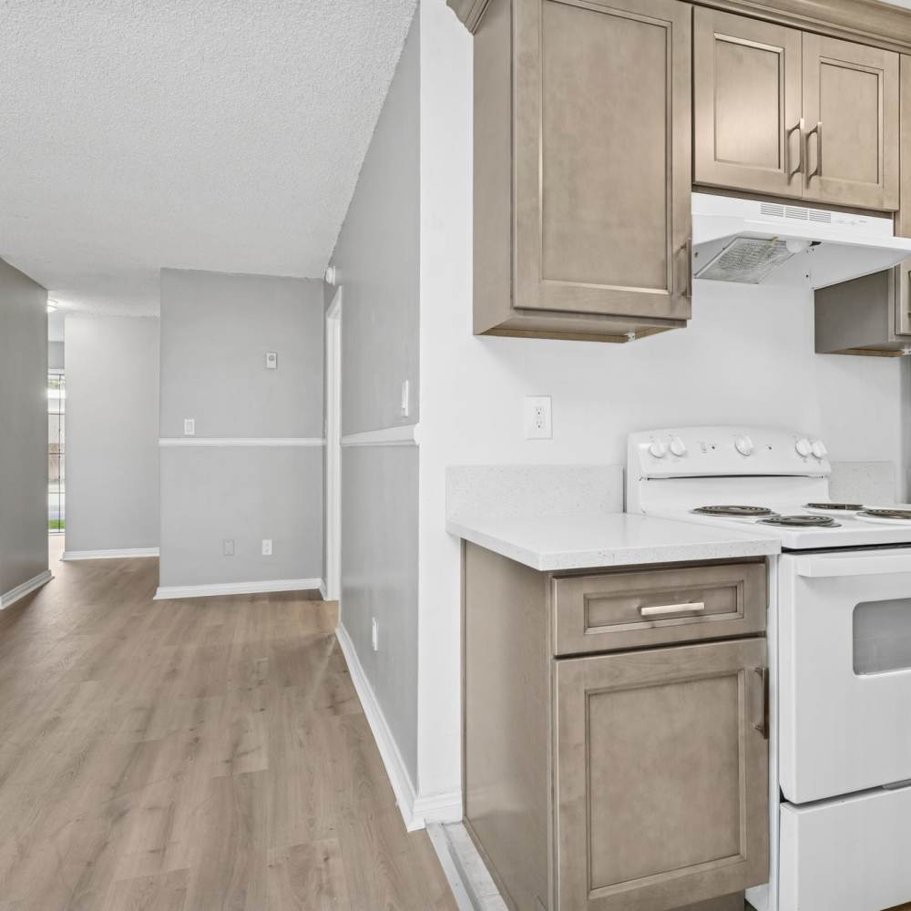 Modern kitchen with white appliances, wood cabinet and large window at Newland Garden Apartments in Garden Grove, California
