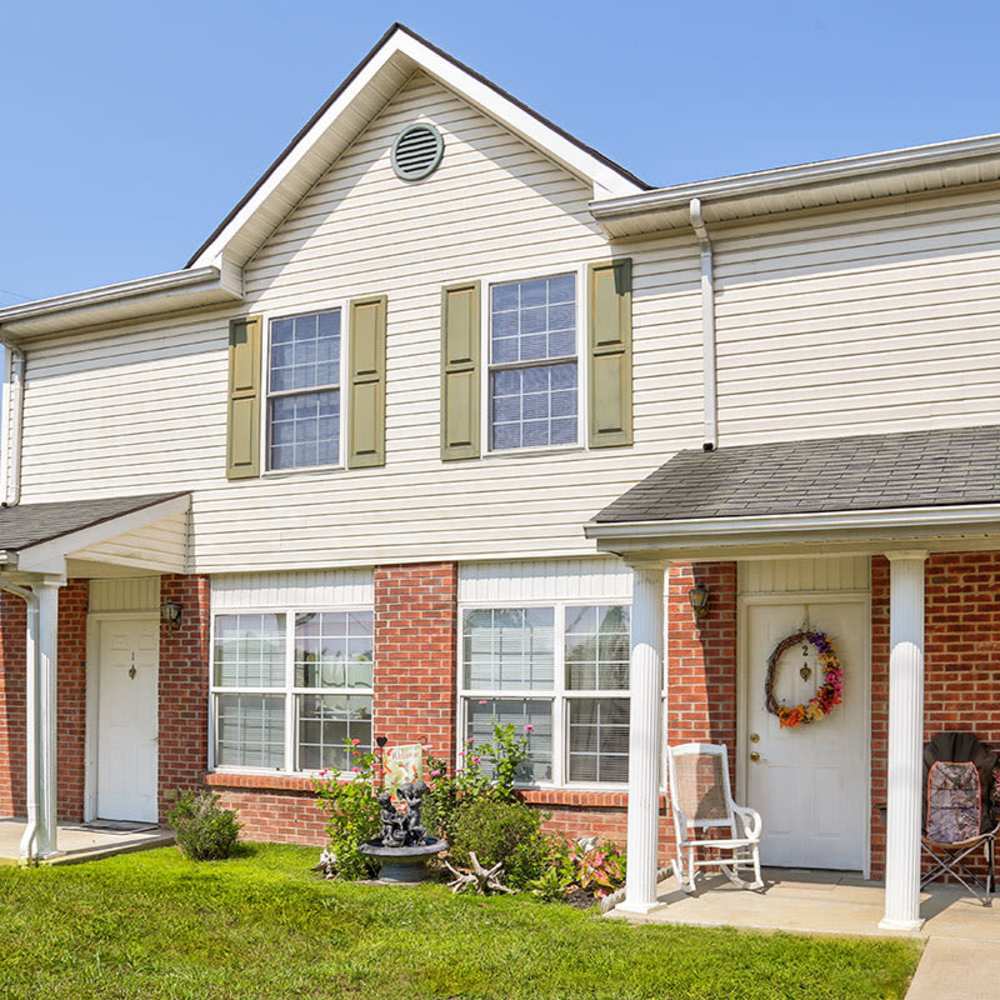 Two-story apartment building with brick accents, green shutters, and a welcoming front porch at Arlington Greene in London, Kentucky