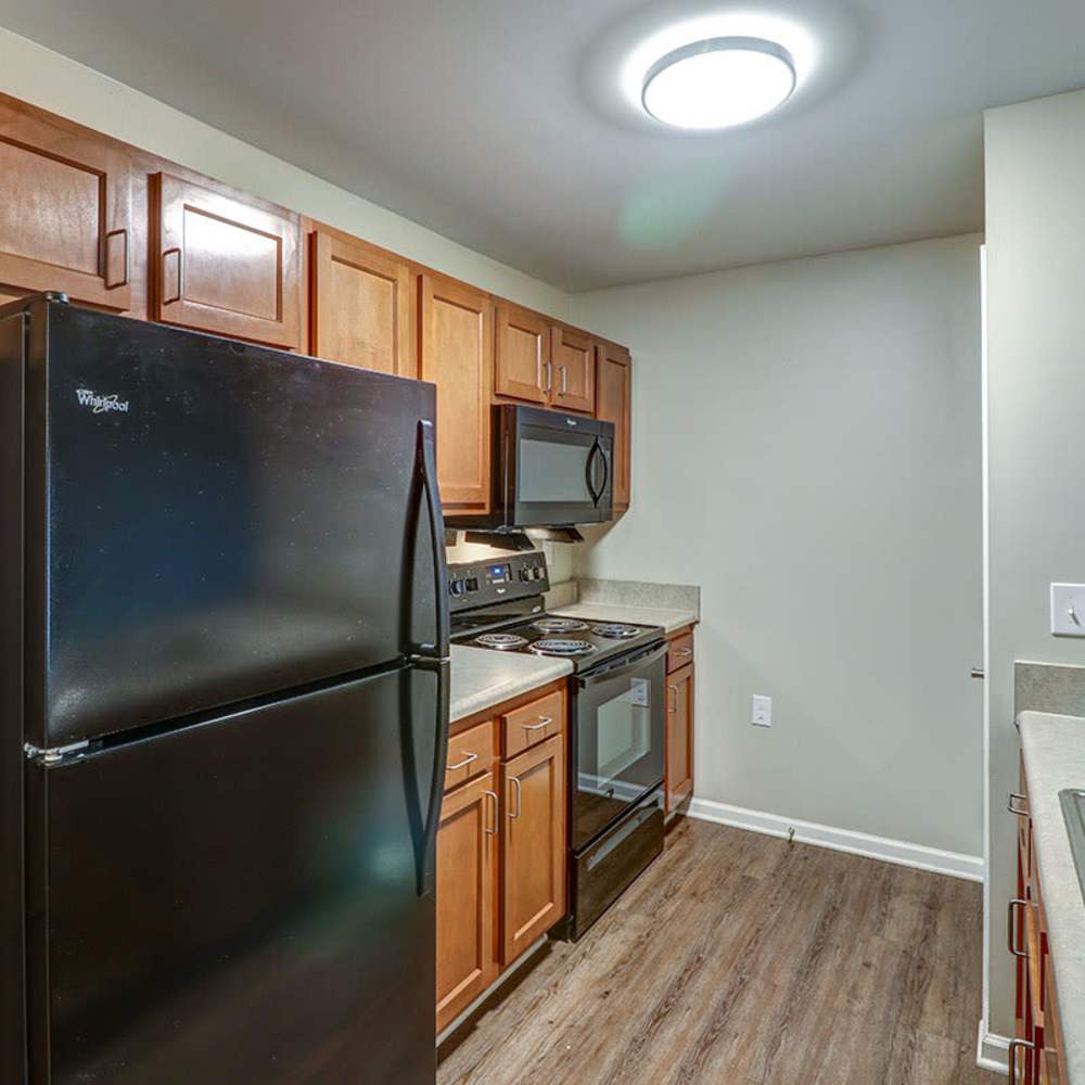Modern kitchen with stainless-steel appliances, granite countertops, wood-style flooring, and ample cabinetry at Oliver Crossing in Linden, Tennessee