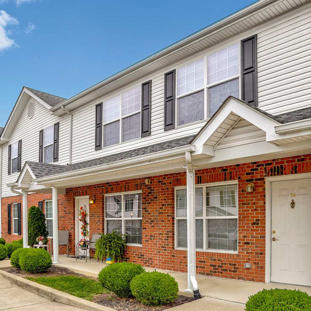 Two-story apartment community with brick exterior, manicured shrubs, and welcoming front porches at Sawgrass Greene in Grayson, Kentucky