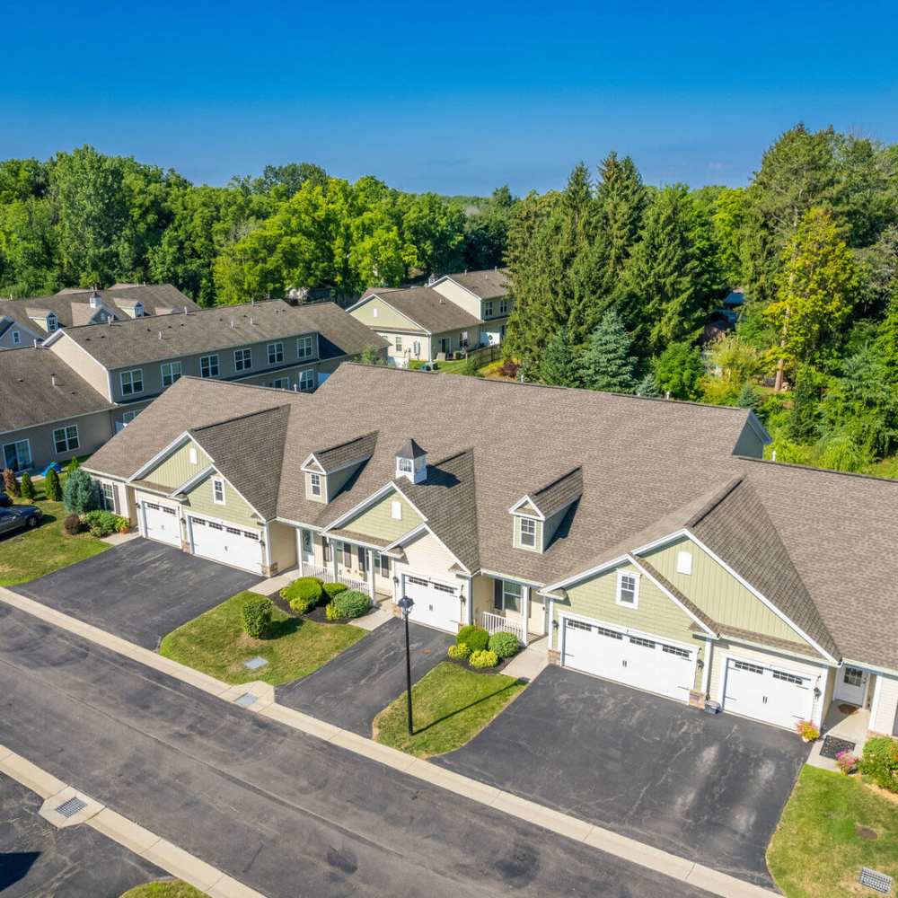 Aerial view of apartment community with landscaped lawns and paved driveways at Carriages At Cedar Rock in Webster, New York