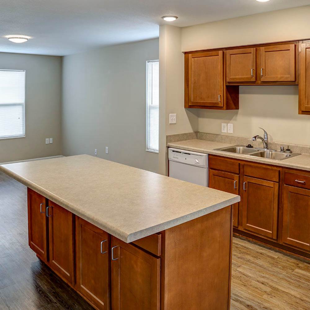 Open layout kitchen with granite countertops, stainless steel appliances, and wood-style flooring at Brea's Crossing Senior Living II in Shelbyville, Kentucky