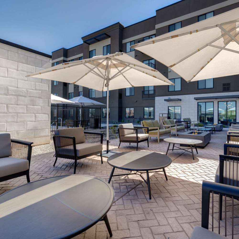 Outdoor lounge with shaded seating, BBQ grills, and landscaped surroundings at Waterwalk Tucson in Tucson, Arizona