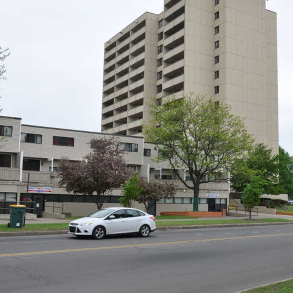 Apartment building exterior with trees at Los Flamboyanes in Rochester, New York
