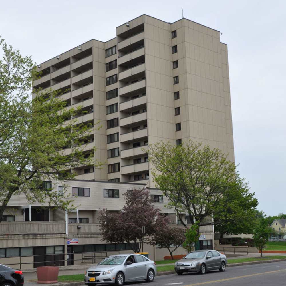 Building exterior with trees at Los Flamboyanes in Rochester, New York