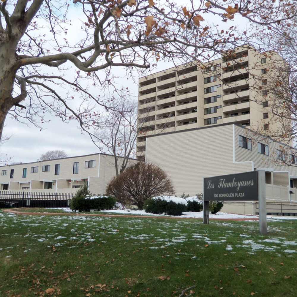 Apartment building exterior with sign at Los Flamboyanes in Rochester, New York