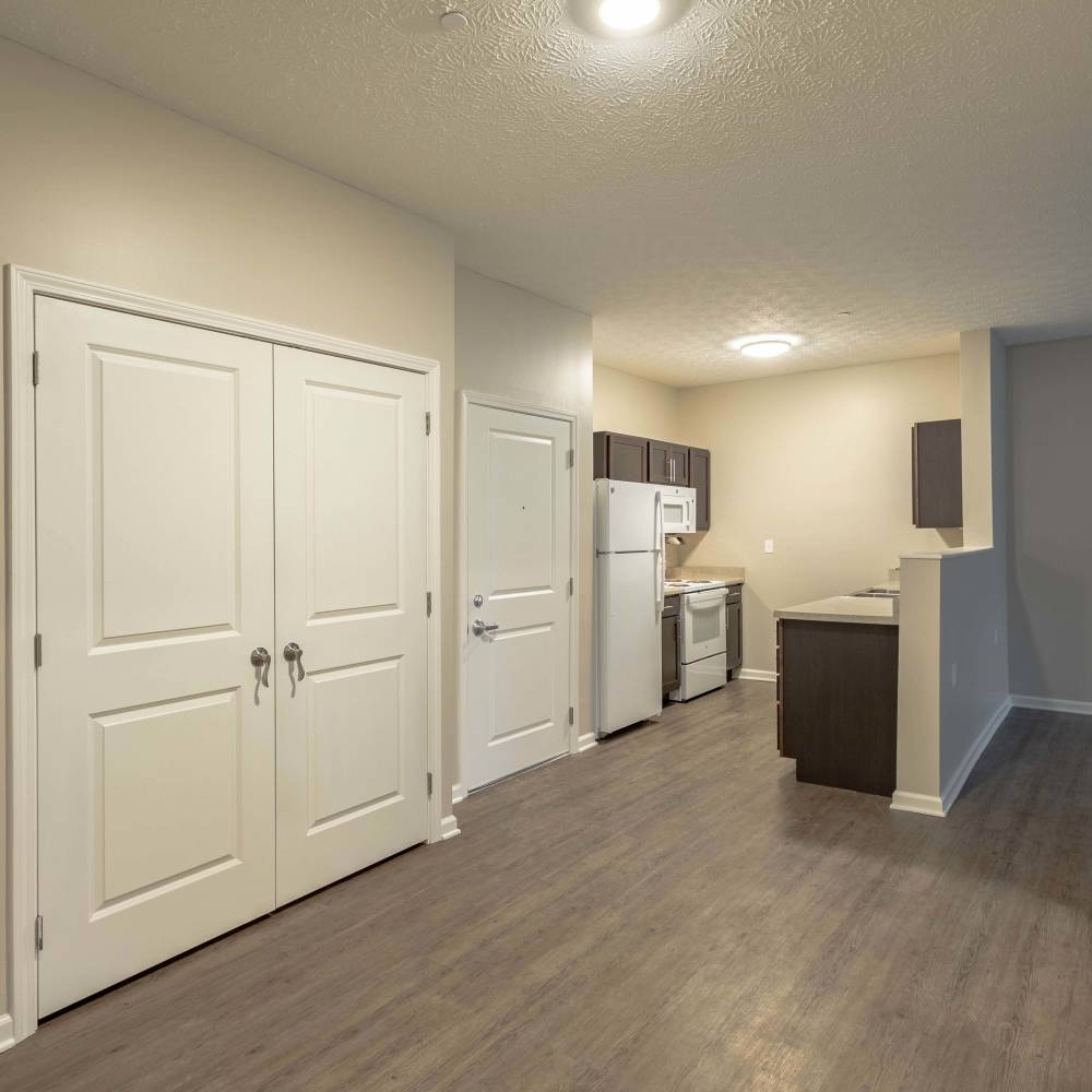 Open layout living room with wood-style flooring at Beaumont Greene Senior Living in Athens, Ohio