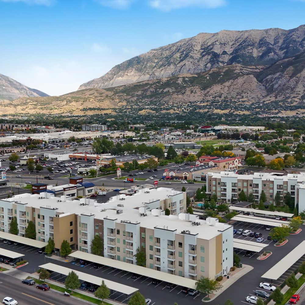 Aerial view of modern apartment community with covered parking and surrounding mountains at Canyon View Crossing in Orem, Utah