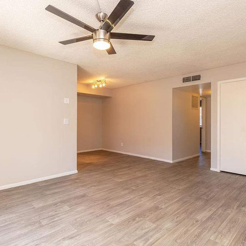 Spacious living area with wood-style flooring and ceiling fan, open layout for versatile living at Fairways on Thunderbird in Phoenix, Arizona