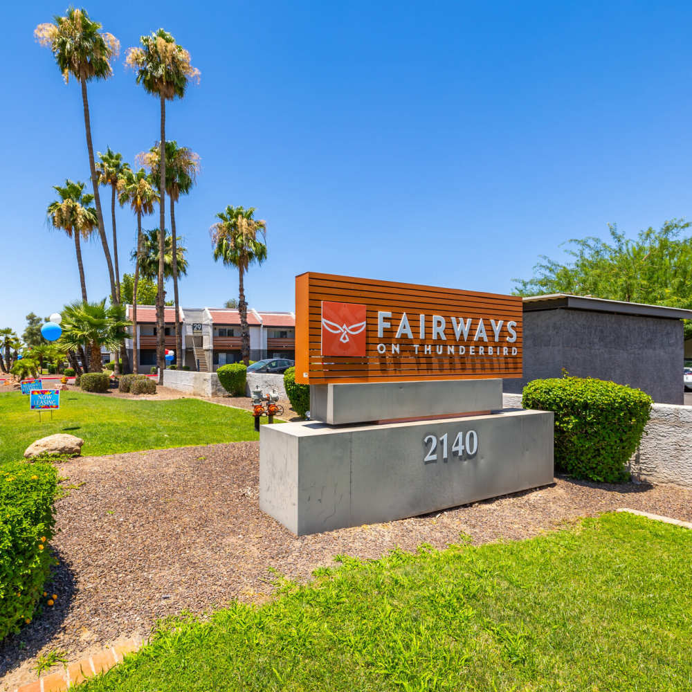 Community sign with palm trees and landscaped greenery in a sunny environment at Fairways on Thunderbird in Phoenix, Arizona