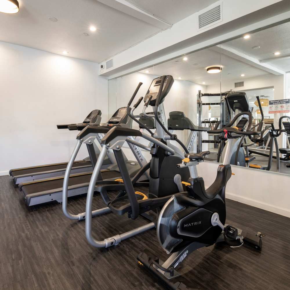 Modern fitness center with treadmills, elliptical machines, and wood-style flooring at Fairways on Thunderbird in Phoenix, Arizona