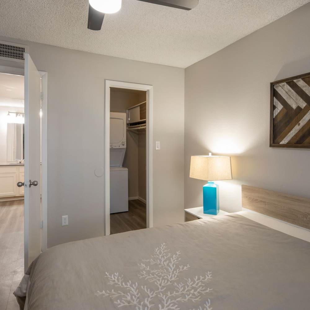 Cozy bedroom with wood-style flooring, ceiling fan, and laundry closet visible through doorway at Fairways on Thunderbird in Phoenix, Arizona