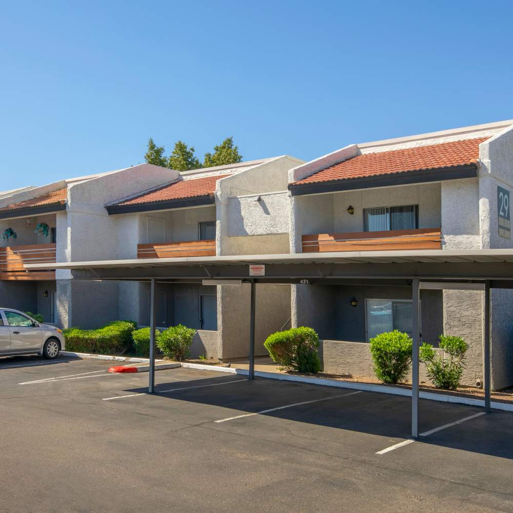 Two-story apartment community with covered parking and balconies, surrounded by green landscaping at Fairways on Thunderbird in Phoenix, Arizona