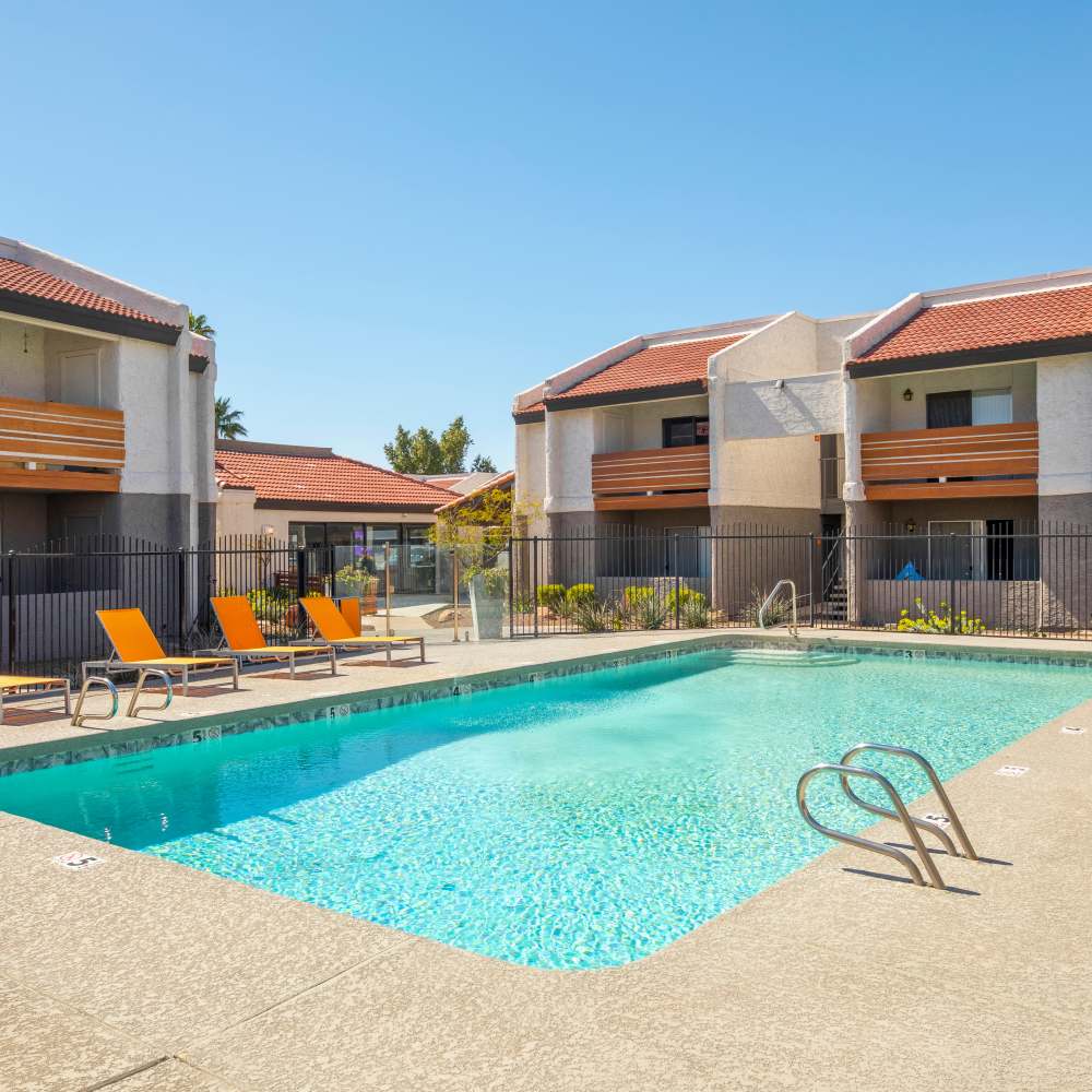 Sparkling pool with lounge chairs and gated entrance to apartment community at Fairways on Thunderbird in Phoenix, Arizona
