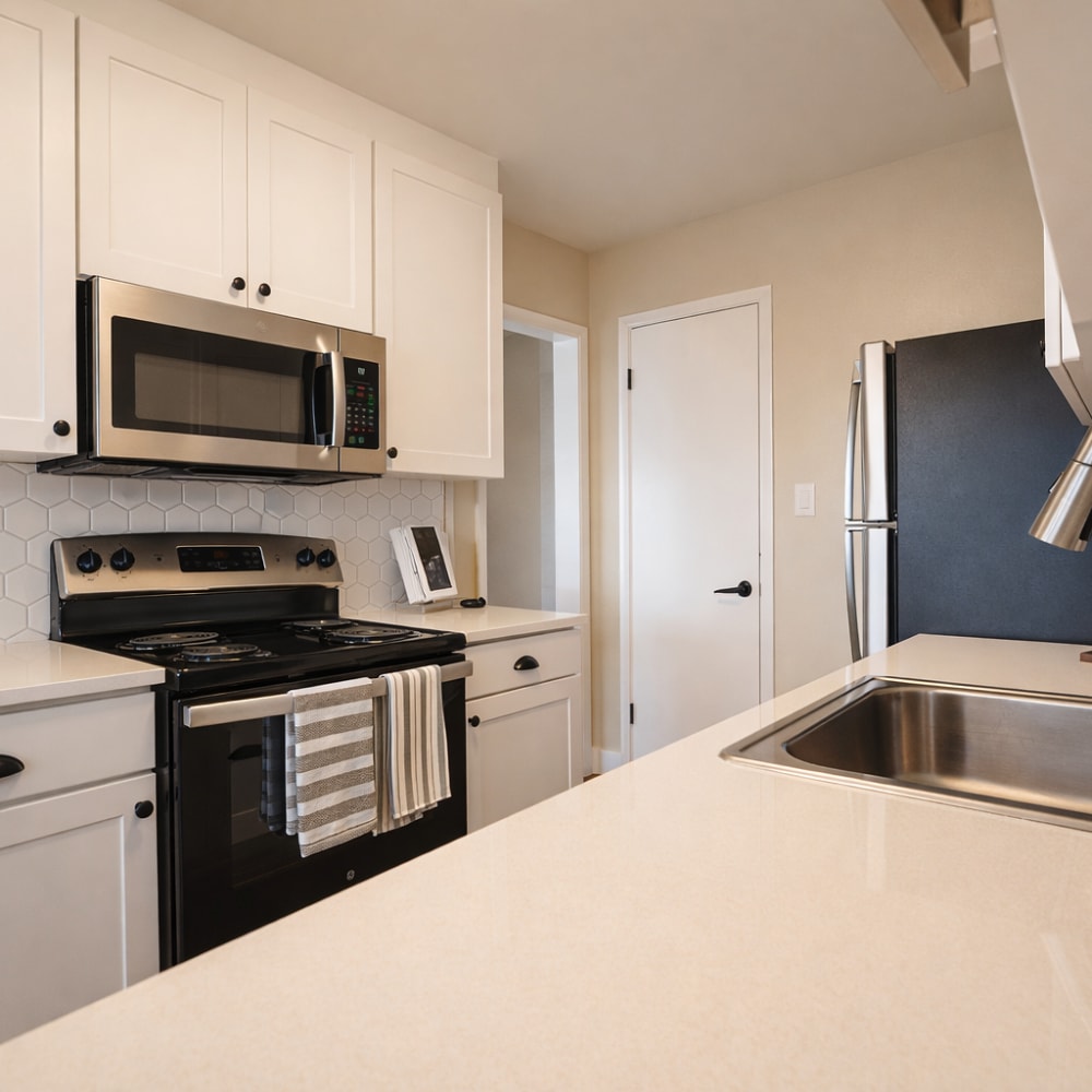 Kitchen with stainless steel appliances, white cabinets and backsplash at Crestview Terrace in Hayward, California