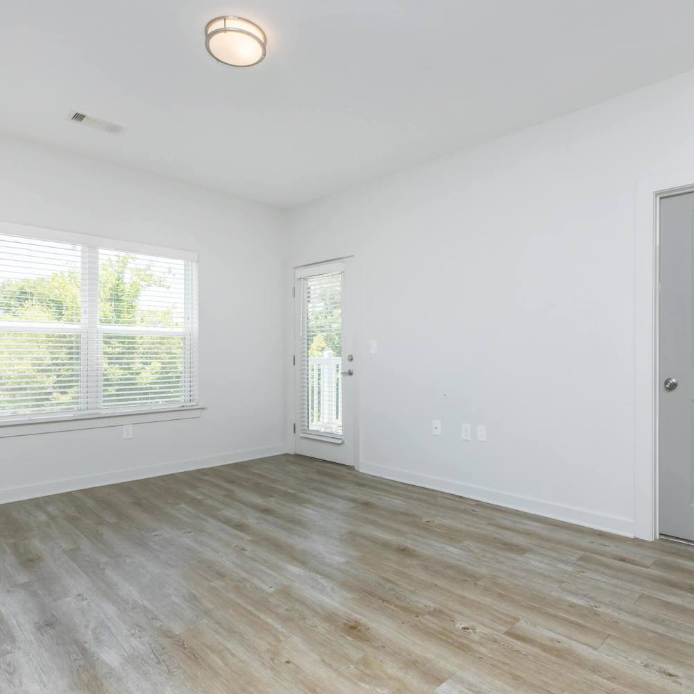 Bright living room with wood-style flooring and large windows leading to a private balcony at The Arcadia in Madison, Tennessee